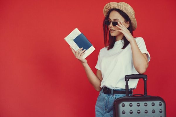 stylish-girl-posing-with-travel-equipment-red-wall_1157-34335